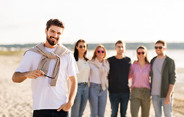 Image showing happy man with friends on beach in summer