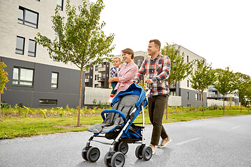 Image showing family with baby and stroller walking along city