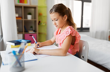 Image showing student girl with book writing to notebook at home