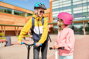 Image showing happy school children with backpacks and scooters