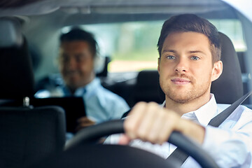 Image showing male taxi driver driving car with passenger