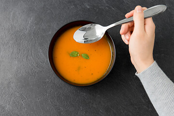 Image showing hands with bowl of pumpkin cream soup on table