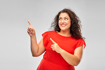 Image showing happy woman in red pointing fingers at something