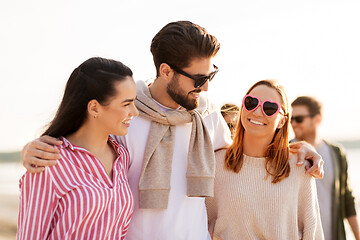 Image showing happy friends walking along summer beach