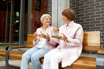 Image showing senior women eating takeaway food on city street