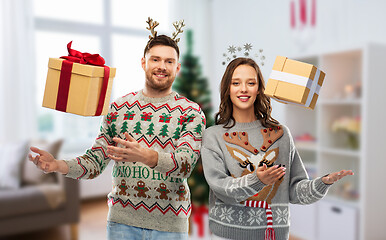 Image showing happy couple in christmas sweaters with gift boxes