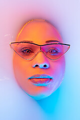 Image showing Beautiful female face in the milk bath with soft glowing in blue-pink neon light