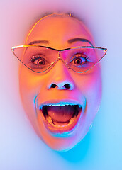 Image showing Beautiful female face in the milk bath with soft glowing in blue-pink neon light