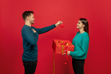 Image showing Beautiful couple in love on red studio background. Valentine\'s Day, love and emotions concept