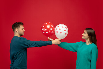 Image showing Beautiful couple in love on red studio background. Valentine\'s Day, love and emotions concept