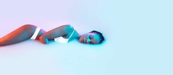 Image showing Beautiful female body in the milk bath with soft glowing in blue-pink neon light