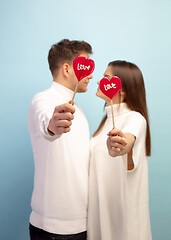 Image showing Beautiful couple in love on blue studio background. Valentine\'s Day, love and emotions concept