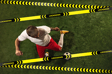 Image showing Football or soccer player on grass background behind limiting tapes with word Lockdown