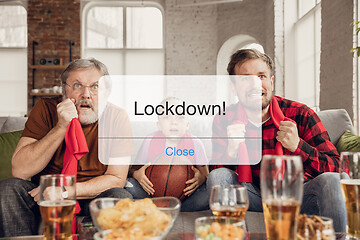 Image showing Excited, shocked soccer fans cheering for favourite sport team in restaurant or home behind the message with word Lockdown