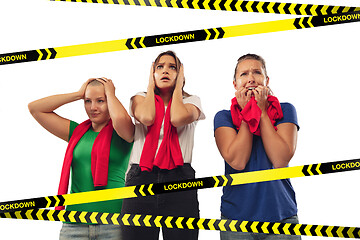 Image showing Excited, shocked female soccer fans cheering for favourite sport team isolated on white background with limiting tapes with word Lockdown