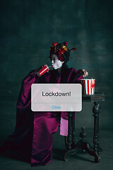 Image showing Young japanese woman as geisha isolated on dark green background. Drinking cola and eating popcorn behind limiting message lockdown on the screen