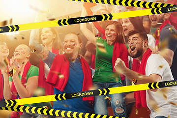 Image showing Female and male soccer fans cheering for favourite sport team with bright emotions, excited, wondered behind the limiting tapes with Lockdown