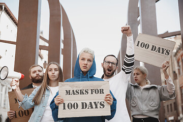 Image showing Group of activists protesting, supporting masks for 100 days in America. Look angry, hopeful, confident. Banners and smoke. Coronavirus.