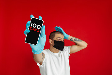 Image showing Man wearing protective face mask shows phone with sign masks for 100 days in USA, America on screen