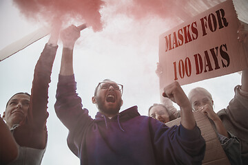 Image showing Group of activists protesting, supporting masks for 100 days in America. Look angry, hopeful, confident. Banners and smoke. Coronavirus.