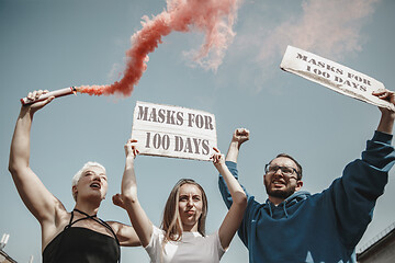 Image showing Group of activists protesting, supporting masks for 100 days in America. Look angry, hopeful, confident. Banners and smoke. Coronavirus.