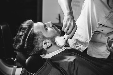 Image showing Client during beard shaving at barbershop.