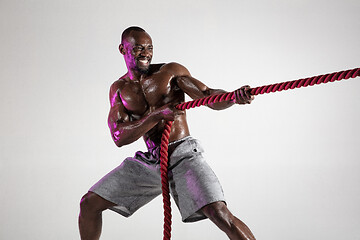 Image showing Young african-american bodybuilder training over grey background