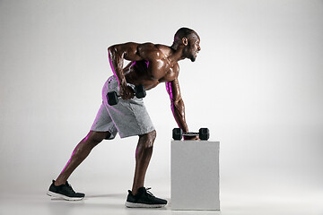 Image showing Young african-american bodybuilder training over grey background