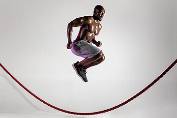 Image showing Young african-american bodybuilder training over grey background