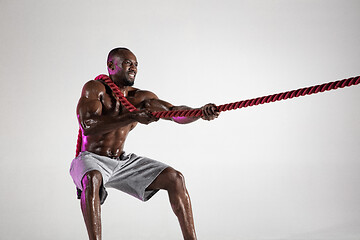 Image showing Young african-american bodybuilder training over grey background