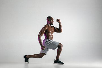 Image showing Young african-american bodybuilder training over grey background