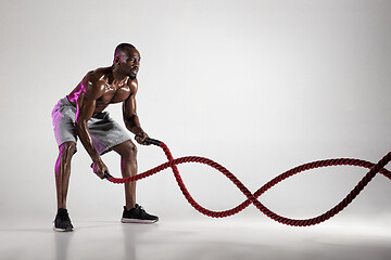 Image showing Young african-american bodybuilder training over grey background