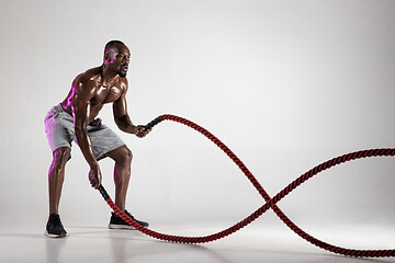 Image showing Young african-american bodybuilder training over grey background