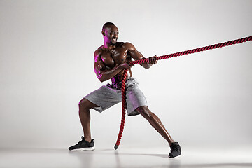 Image showing Young african-american bodybuilder training over grey background