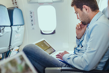 Image showing Businessman working with laptop on commercial airplane.