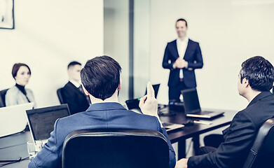 Image showing Successful team leader and business owner leading informal in-house business meeting. Businessman working on laptop in foreground. Business and entrepreneurship concept