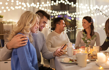 Image showing happy couple with smartphone at family tea party