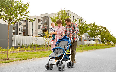 Image showing family with baby and stroller walking along city