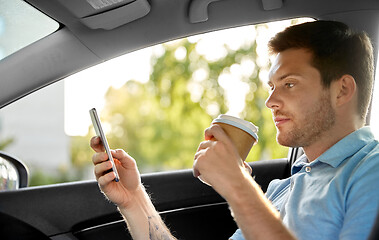 Image showing passenger drinking coffee using smartphone in car