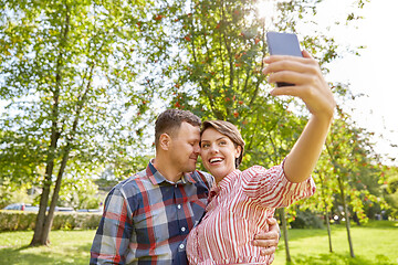 Image showing happy couple in park taking selfie by smartphone