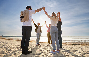 Image showing happy friends holding hands on summer beach