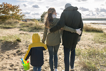 Image showing happy family walking along autumn beach
