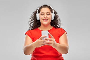 Image showing woman in headphones listens to music on smartphone