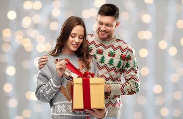 Image showing happy couple in christmas sweaters with gift box