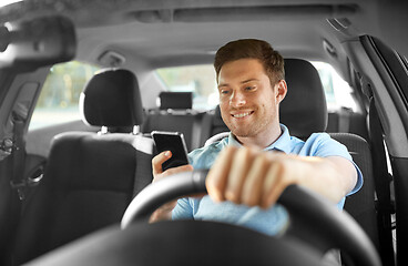 Image showing man driving car and using smartphone