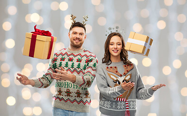 Image showing happy couple in christmas sweaters with gift boxes