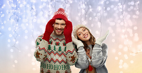 Image showing couple in ugly sweaters and mittens on christmas