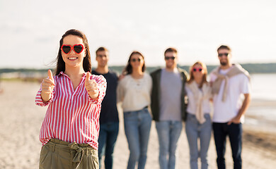 Image showing woman with friends on beach showing thumbs up