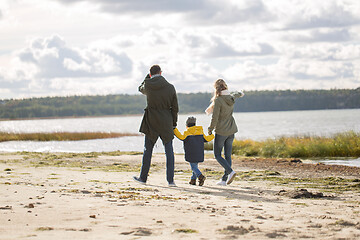 Image showing happy family walking along autumn beach