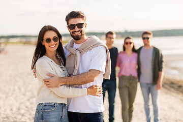 Image showing happy couple with friends on beach in summer